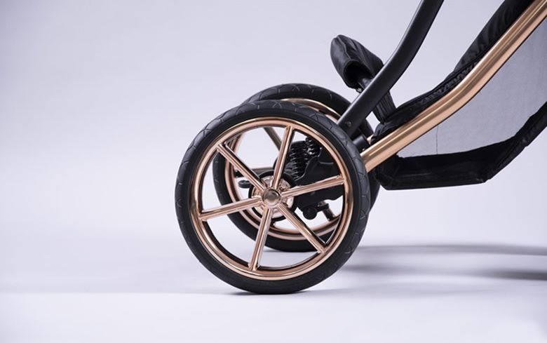 Nowoczesne koła do wózka dziecięcego z metalicznymi detalami w kolorze rose gold i widoczną amortyzacją